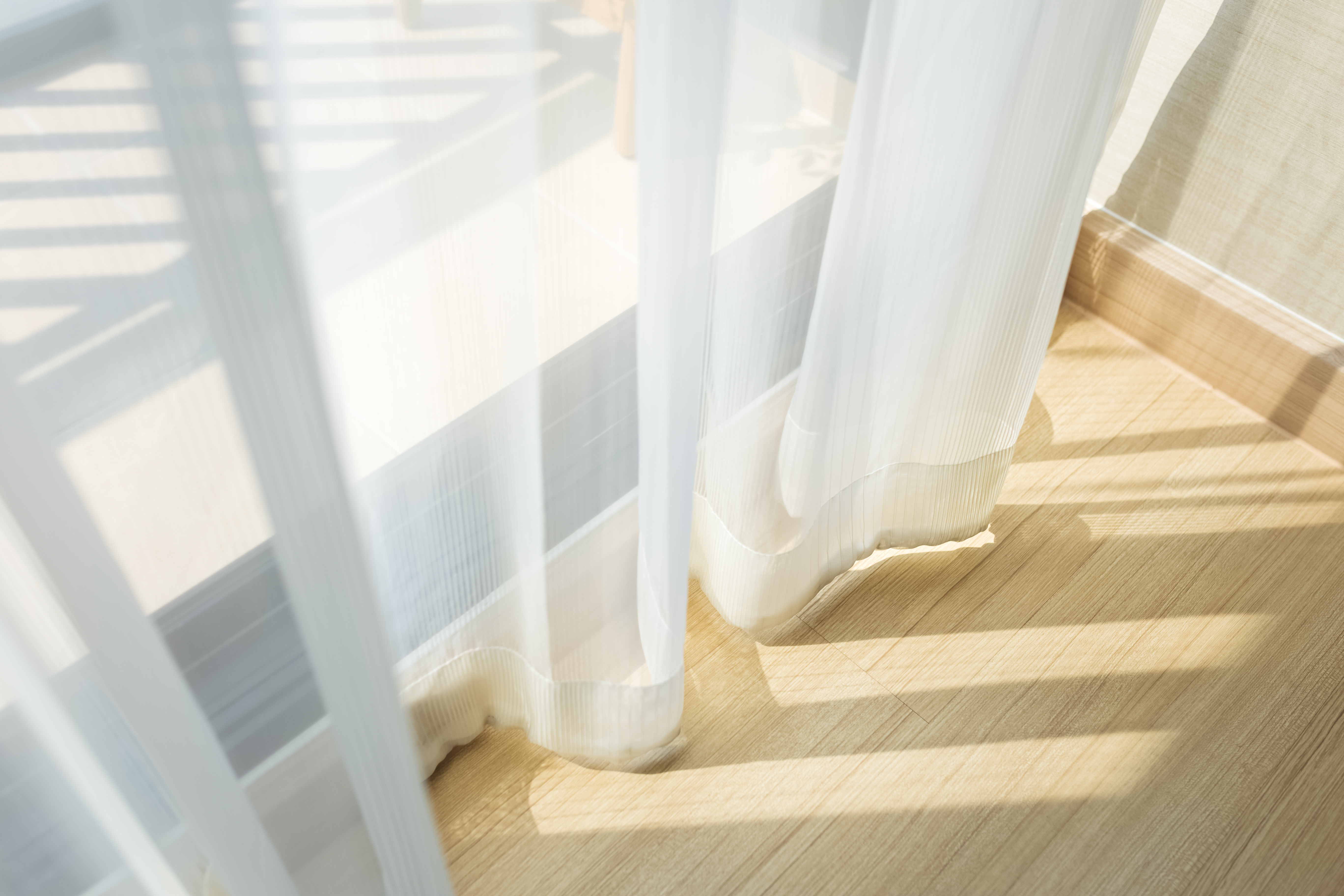 Soft morning light filtering through sheer curtains into a quiet, still room at home, gentle and calm