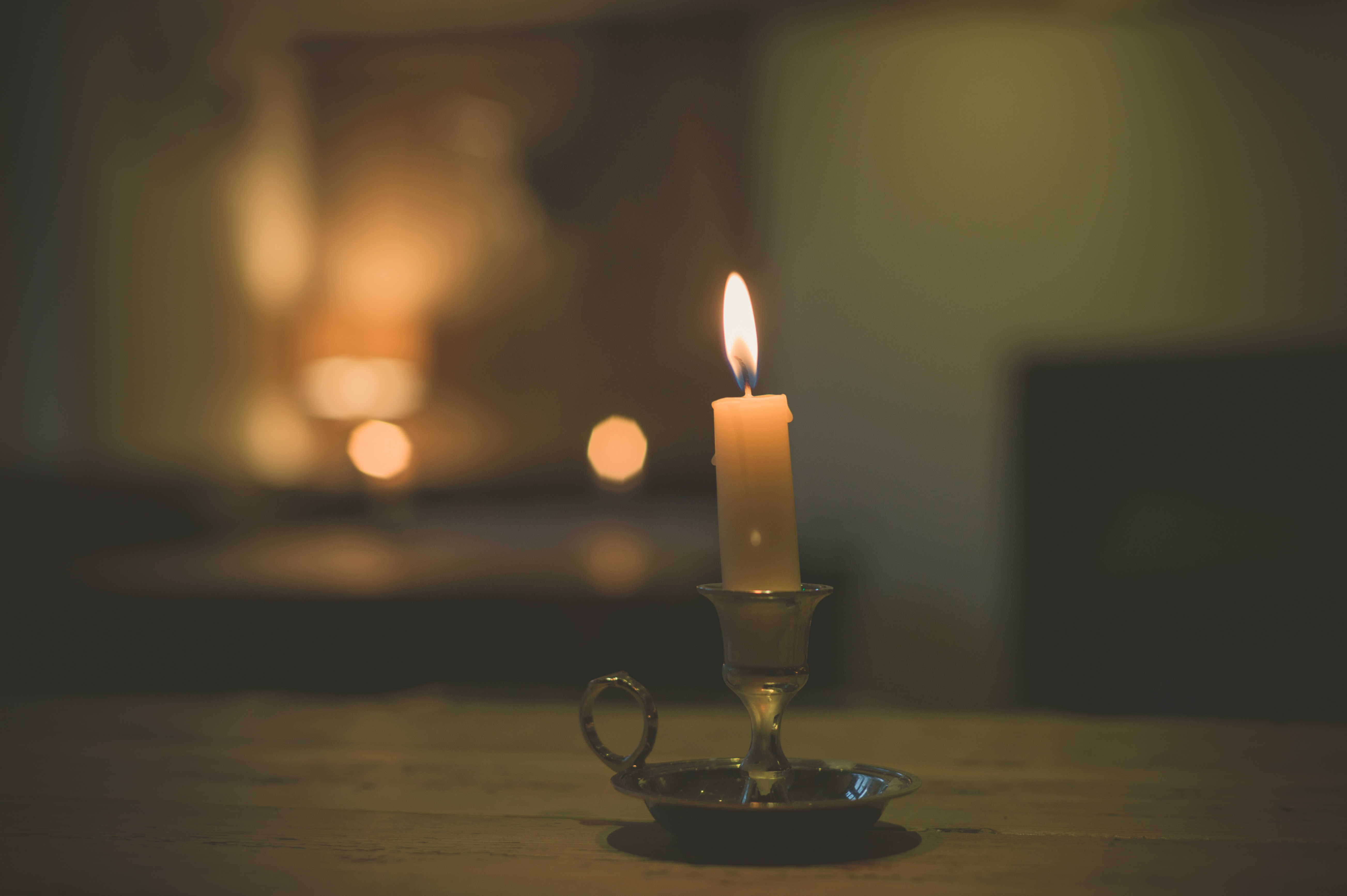 One small candle burning on a wooden dining table in a softly lit room, a simple way to hold a place for a baby at a holiday meal