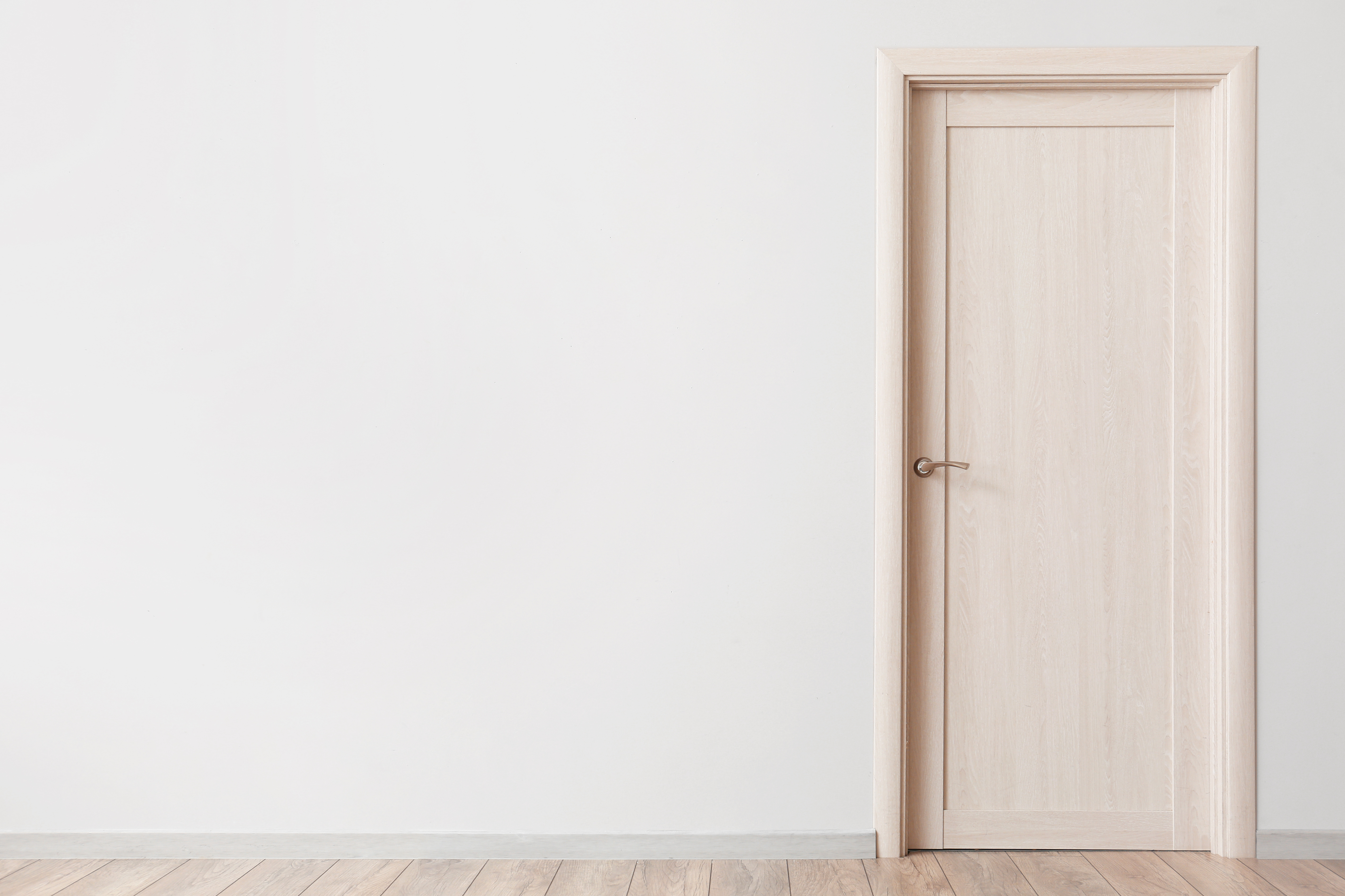 A plain wooden door in a softly lit wall, the quiet threshold between home and the world outside after loss