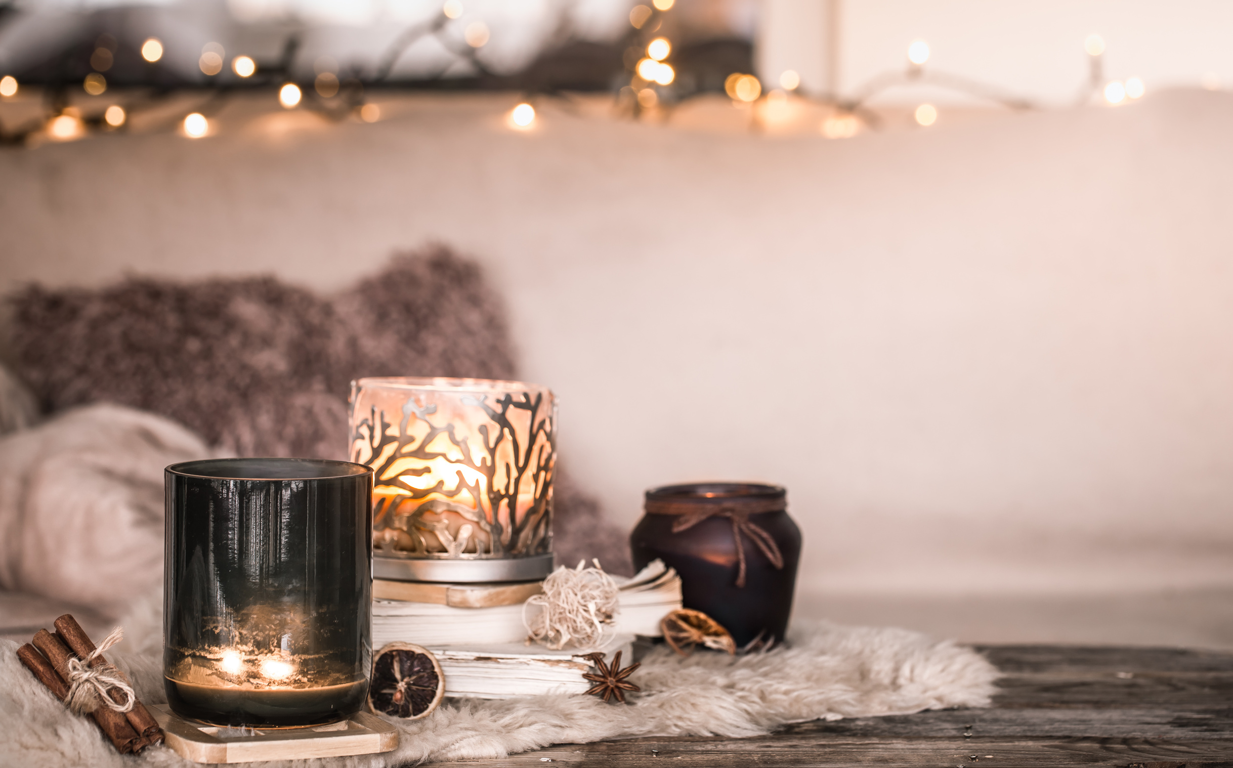 Lit candles beside an open book and soft folded blankets, a small corner of home arranged for a quiet evening