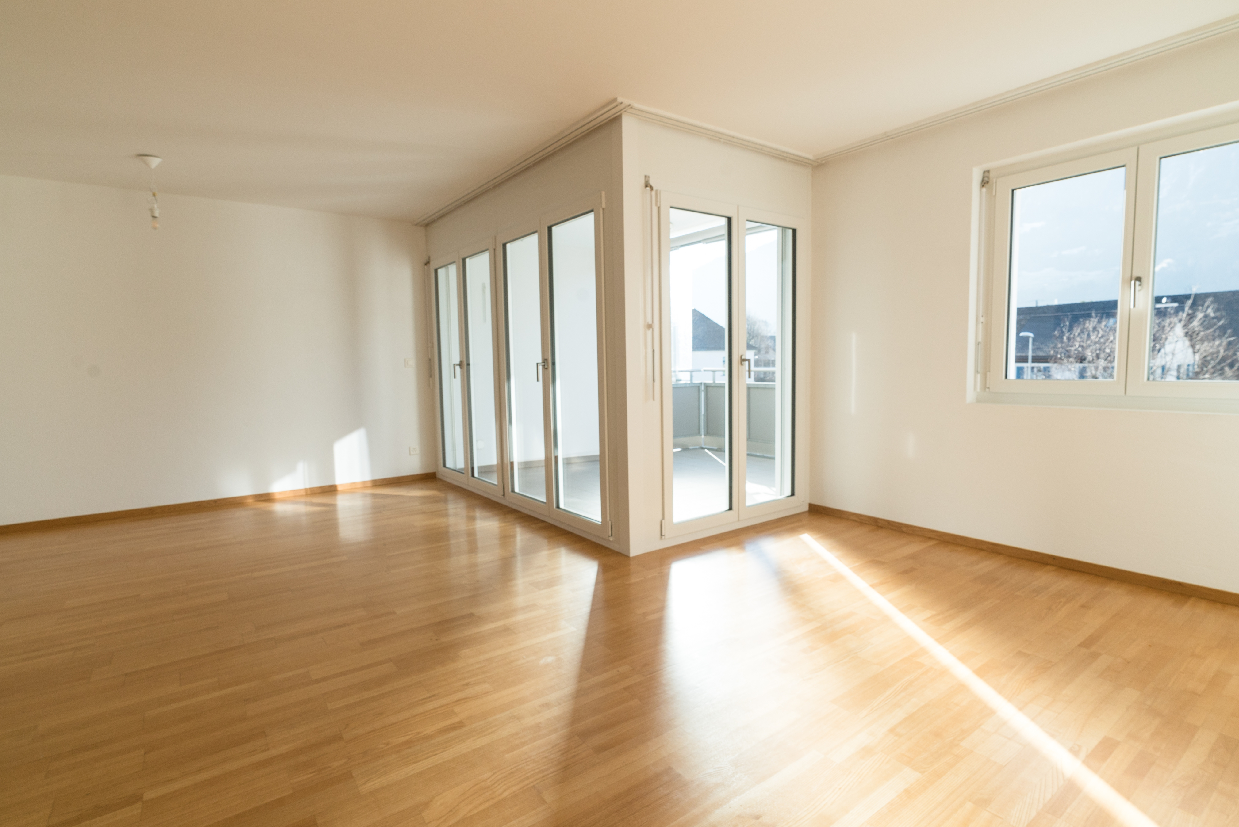 An empty room with bare wooden floors and daylight coming through tall doors, waiting to be either left behind or unpacked into after a loss