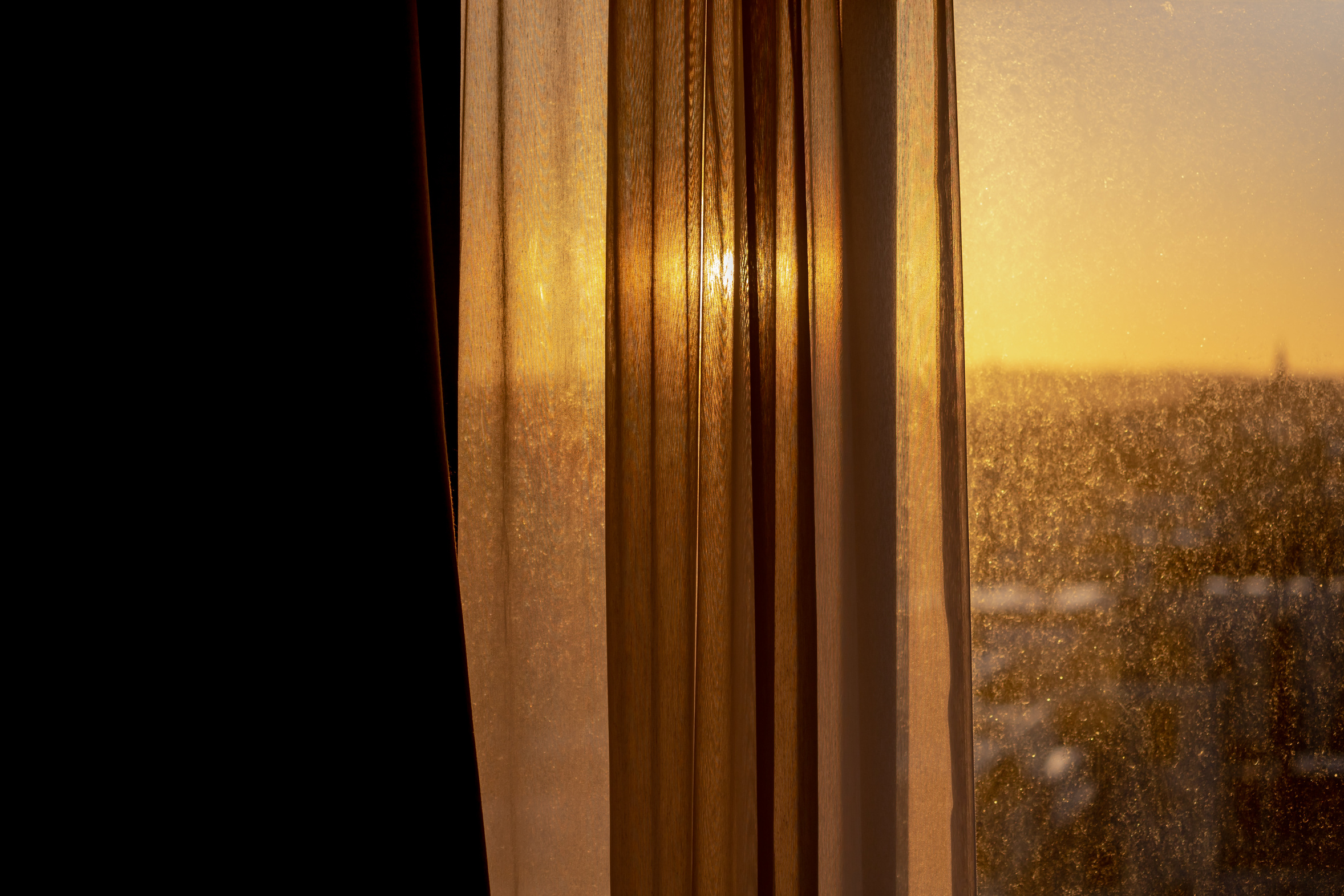 Sheer white curtains at a bedroom window with soft winter daylight coming through on a quiet afternoon